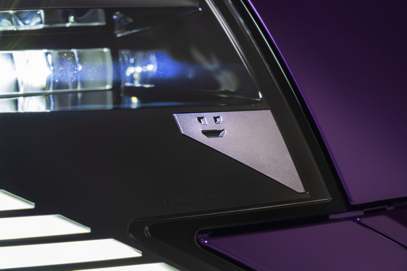 Close-up of the Nissan PIXO front headlight, featuring a small geometric face motif integrated into the lighting design.
